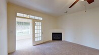 Located at 5124 Southwind Rd in Greensboro, NC, this single-story home offers a well-designed layout with a variety of comfortable living spaces. The spacious living room is a central highlight, featuring a corner fireplace, plush carpeting, a ceiling fan, and a set of French doors topped with transom windows that invite abundant natural light and provide access to the outdoors. Adjacent to the living area, a dedicated room impresses with tall arched windows that frame views of the surrounding greenery, creating a bright and airy atmosphere. The kitchen is outfitted with white cabinetry, granite-look countertops, stainless steel appliances including a refrigerator, dishwasher, microwave, and range, all complemented by warm hardwood-style flooring. The bedrooms are carpeted and generously sized, offering ample closet space and a calm, neutral palette. The bathroom features white cabinetry with under-sink storage, a large vanity mirror, hardwood-style flooring, and a tub-shower combination. Throughout the home, cream-toned walls and consistent finishes create a cohesive and inviting ambiance suited for comfortable everyday living.