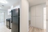 This single-story residence features a clean, updated interior with a cohesive neutral palette and light wood-look flooring running throughout the main living areas and bedrooms. The living room serves as a welcoming central space, highlighted by a classic brick fireplace, a sliding glass door with vertical blinds leading to an outdoor area, and an adjacent window that allows natural light to fill the room. A dining area sits just off the kitchen, also with access to the outdoors via a sliding glass door.

The galley-style kitchen is well-appointed with white shaker cabinetry, granite-look countertops, white subway tile backsplash, and black appliances including a gas range and refrigerator. A stainless steel sink and ample cabinet storage on both sides of the kitchen contribute to its functional layout.

The bedrooms are comfortably sized, each featuring light wood flooring, ceiling fans with integrated lighting, and natural light from windows. Sliding closet doors provide built-in storage in at least one bedroom.

Two bathrooms serve the unit. One features a tiled walk-in shower with glass enclosure and a white vanity, while the second offers a tub-shower combination with sliding glass doors, large-format tile surround, and white tile flooring—both finished in a bright, clean style.