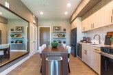 Located at 2230 Calle de Luna in Santa Clara, CA, this thoughtfully designed one-bedroom, two-bathroom residence offers a cohesive modern aesthetic across its single floor. The open-concept layout seamlessly connects the kitchen, dining area, and living room, creating an efficient yet inviting communal space. The kitchen is outfitted with light wood cabinetry, stainless steel appliances including a French door refrigerator, dishwasher, range, and microwave, complemented by a white tile backsplash and clean countertops. A wood dining table anchors the adjacent dining area, which flows naturally into the living room. The living room features large windows that frame sweeping outdoor views, filling the space with abundant natural light. The bedroom also benefits from generous windows with the same scenic views, enhancing its calm atmosphere with light wood flooring. Both bathrooms are stylishly finished — one features bold geometric patterned wallcovering, a walk-in glass shower with white tile surround, and a vanity with an illuminated mirror. A dedicated closet and in-unit laundry add practical convenience. Light wood flooring runs throughout, tying together the space's contemporary, warm character.
