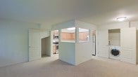 This single-floor residential space offers a clean, functional layout designed for comfortable everyday living. The open-concept design centers around a pass-through kitchen that connects seamlessly to the main living area, creating an airy and cohesive flow throughout. The kitchen is well-appointed with light wood cabinetry providing ample storage, stainless steel appliances including a range, microwave, and refrigerator, and a bright overhead skylight that draws natural light into the space. The pass-through counter adds a social element, making it easy to interact between the kitchen and living areas. The living area features neutral wall tones and soft carpeting underfoot, contributing to a warm and inviting atmosphere. Multiple doorways lead to additional rooms, suggesting a thoughtful floor plan with defined spaces for rest and utility. The consistent use of white walls and light finishes throughout lends the space a bright, clean aesthetic. Overall, this residence offers a practical and comfortable environment with a straightforward layout, modern kitchen amenities, and a neutral palette that provides a versatile canvas for personalization.