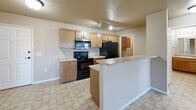 Located at 4500 E 33rd St in Sioux Falls, SD, this one-bedroom, one-bathroom unit offers a well-organized single-floor layout with a practical and comfortable design throughout. The heart of the unit is an open-concept space that seamlessly combines the kitchen, dining, and living areas. The kitchen is equipped with warm wood cabinetry, black appliances including a range, microwave, and refrigerator, a peninsula with a breakfast bar, and a double sink — all set on easy-care tile flooring. The living area transitions naturally from the kitchen and features plush carpet, neutral-toned walls, and a glazed door leading to a private balcony, accompanied by a large window that draws in natural light and outdoor views. The bedroom is a comfortable, carpeted retreat with a window overlooking the surroundings and access to a closet. The bathroom is finished with tile flooring, a wood vanity with mirror, and a walk-in shower with a glass sliding door. A dedicated laundry room houses a stacked washer and dryer unit. Additional storage is provided through three closets distributed throughout the unit, and a hallway connects the spaces efficiently. The textured ceilings and warm, neutral palette lend a cohesive, move-in-ready feel to the entire space.