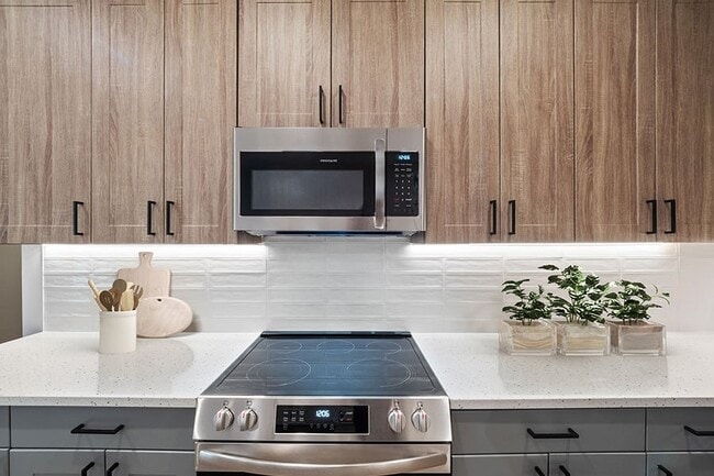 Elegantes gabinetes de cocina europeos de dos tonos con iluminación debajo de los gabinetes y puertas y cajones con cierre suave. - The Henslow Daniel Island Apartments & Tow...