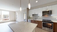 Located at 505 Lincoln Ave in San Jose, CA, this single-story unit offers a thoughtfully designed layout with modern finishes throughout. The kitchen serves as a centerpiece of the space, featuring a striking two-tone design with high-gloss white upper cabinetry and warm wood-toned lower cabinets. Stone-look countertops extend across the workspace and onto a generously sized island, complemented by a textured tile backsplash. A full suite of stainless steel appliances includes a refrigerator, range, microwave, and dishwasher, making the kitchen both functional and visually cohesive.

The living area benefits from large floor-to-ceiling windows that flood the space with natural light and provide views of the surrounding neighborhood. Light wood-tone flooring runs throughout, contributing to the unit's clean, contemporary aesthetic. A wall-mounted mini-split system ensures comfortable climate control year-round.

Two bathrooms serve the unit, each finished with wood-tone vanities, neutral stone-look countertops, and hardwood-style flooring. One bathroom features a spacious glass-enclosed walk-in shower, while the other includes a well-sized vanity with ample storage. The overall design maintains a consistent modern palette of warm neutrals and quality materials.