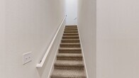 Located in Clermont, FL, this two-story, 2-bedroom, 2-bathroom home offers a clean, modern aesthetic throughout its thoughtfully designed floor plan. The entry level provides access to the main living area, where an open-concept kitchen and living room create a bright, connected space. The kitchen is outfitted with white flat-panel cabinetry, granite countertops, a gray subway tile backsplash, and stainless steel appliances including a French door refrigerator, electric range, and microwave. Light wood-style flooring runs through the main living areas, adding warmth to the crisp white walls.

A carpeted staircase with a white handrail leads to the upper floor, where both bedrooms are located. The primary bedroom is generously sized and features a ceiling fan, natural light from windows with blinds, and access to a private en-suite bathroom. The en-suite showcases a walk-in glass shower with tile surround, a dual-sink vanity with granite countertops, white cabinetry, and wood-style flooring. The second bedroom also features carpet, a ceiling fan, and a window for natural light. A dedicated laundry room with full-size washer and dryer hookups adds everyday convenience. Three closets throughout provide ample storage space.