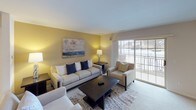 This thoughtfully designed single-floor residence offers a comfortable and functional layout across several well-defined living spaces. The living room serves as the heart of the home, featuring plush carpeting, a tile-surround gas fireplace, a wall-mounted television, and a large sliding glass door that opens to a private balcony with exterior views, filling the room with natural light. Adjacent to the living area, the dining room accommodates a full-sized dining table beneath a stylish pendant light fixture, complemented by warm neutral tones on the walls. The galley-style kitchen is outfitted with honey-toned wood cabinetry, dark granite-style countertops, tile flooring, and a full suite of appliances including a gas range, built-in microwave, and refrigerator. The primary bedroom offers carpeted flooring, generous closet space, and a private en-suite bathroom featuring tile flooring, a vanity with ample counter space, and clean white finishes. A second well-sized bedroom includes carpet, a large window with vertical blinds, and easy access to a second full bathroom with a wide vanity and mirror. Throughout the residence, a cohesive neutral color palette, flush-mount lighting, and consistent finishes create a clean and inviting atmosphere.