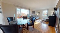 This single-floor, 1-bedroom, 1-bathroom residence in Delaware offers a well-organized and comfortable layout filled with natural light throughout. The combined living and dining area serves as the heart of the home, featuring warm hardwood flooring, crown molding, and large windows that invite generous sunlight. A sliding glass door connects the living space to the outdoors, framing pleasant exterior views. The dining area accommodates a round glass-top table with upholstered chairs, while the living room provides a cozy setting with a cushioned sofa, decorative wall art, and a wall-mounted television. The kitchen is outfitted with warm wood cabinetry, a gas range, full-size refrigerator, and a single-basin sink beneath a window overlooking the outdoors. The bedroom is spacious and bright, benefiting from multiple windows, hardwood floors, a ceiling fan, and ample room for furnishings. A second, more intimate sleeping area offers a quiet retreat with a large window and warm natural light. The full bathroom features retro-style peach tile surrounding the tub-shower combination, a mosaic tile floor, white vanity with storage, and a bright window. Throughout the residence, the consistent use of hardwood floors and neutral tones creates a cohesive and inviting atmosphere.