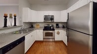 Located at 53 Cedar St in Woburn, Massachusetts, this single-floor residence offers a thoughtfully designed layout with a neutral, modern aesthetic throughout. The entryway greets visitors with warm hardwood flooring, crown molding, and convenient closet storage, setting the tone for the rest of the home.

The kitchen is a functional highlight, featuring white cabinetry, granite-style countertops, and a full suite of stainless steel appliances including a range, built-in microwave, dishwasher, and refrigerator. Hardwood floors carry through this space, adding warmth and continuity.

The living room is carpeted and finished with elegant crown molding, offering a comfortable and inviting atmosphere. Adjacent spaces provide a seamless flow throughout the unit.

Two well-sized bedrooms are finished with plush carpeting and natural light from large windows. Each room offers ample space for furnishings and includes access to closet storage.

The two bathrooms are finished with tile flooring and white cabinetry. The primary bathroom features a generous vanity with a wide mirror and walk-in shower, while the secondary bathroom includes a shower-tub combination and clean, simple finishes. Together, the spaces present a cohesive, comfortable living environment ideal for everyday living.