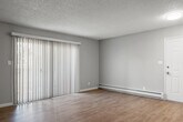 Located at 154 Richardson Drive, Unit 58, in Vallejo, California, this single-floor residence combines practical design with thoughtful updates throughout. The living area is generously proportioned, featuring durable dark hardwood-style flooring, neutral gray walls, and a textured ceiling. A ceiling fan provides year-round comfort, while a baseboard heating system ensures warmth during cooler months. Large sliding glass doors open to a private outdoor area, allowing natural light to fill the room and providing a seamless connection to the exterior. The galley-style kitchen is well-appointed with crisp white shaker cabinetry, light quartz countertops, a black undermount sink, and stainless steel appliances including a refrigerator and range. Light wood-style flooring and a bright overhead fixture give the kitchen a clean, modern feel. A window at the end of the kitchen brings in additional natural light. The bathroom features a full tub and shower combination with a white surround panel system equipped with built-in shelving niches, offering both functionality and a tidy aesthetic. Throughout the unit, white trim and baseboards provide a polished contrast to the neutral wall tones, contributing to a cohesive and well-maintained interior. The overall layout is efficient and move-in ready.