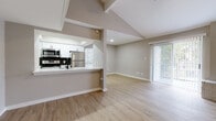 This thoughtfully updated single-floor residence showcases a bright, open-concept design with soaring vaulted ceilings that add a sense of spaciousness to the main living area. Durable light-toned wood-look flooring runs throughout, tying each room together cohesively. The living room benefits from abundant natural light streaming through a large sliding glass door fitted with vertical blinds, which opens to an outdoor area. A built-in brick ledge adds a subtle architectural touch, while a ceiling fan enhances comfort.

The kitchen is designed for both function and style, featuring white shaker cabinetry, quartz-style countertops, and stainless steel appliances including a refrigerator, electric range, and over-the-range microwave. A striking black hexagonal tile backsplash serves as a bold focal point. The kitchen opens to the living space via a pass-through counter, maintaining the home's airy, connected feel.

The bedrooms are generously proportioned, each equipped with ceiling fans, natural light from double windows, and mirrored sliding-door closets offering ample storage. The bathrooms feature clean, modern finishes including white shaker vanities, white quartz countertops, matte black fixtures, and a tub-shower combination accented by elegant marble-look tile surrounds.