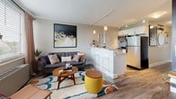 Located at 2000 Riverside Dr in Richmond, Virginia, this thoughtfully designed studio offers an open, single-floor layout that seamlessly integrates living, sleeping, and dining areas into one cohesive space. Hardwood-style flooring runs throughout, providing a warm and consistent foundation underfoot.

The kitchen is a standout feature, showcasing white cabinetry, stainless steel appliances including a refrigerator and range, a breakfast bar with seating, pendant lighting, and track lighting overhead — creating a bright and functional cooking space that flows naturally into the living area.

The living space is well-proportioned, anchored by a large statement wall accented in a bold deep navy, which adds depth and visual interest. A bold, colorful area rug and eclectic furnishings contribute to the space's vibrant, modern character.

A generous window in the living area allows abundant natural light to fill the room while offering treetop views of the surrounding landscape. Elegant drapery and wood blinds provide both style and privacy.

The bathroom features clean white cabinetry and countertops, with a walk-in closet directly adjacent, offering practical and organized storage. The overall ambiance is modern, energetic, and welcoming — ideal for those seeking a stylish urban residence in the heart of Richmond.