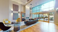 Located at 121 N Second St in Philadelphia's historic Old City neighborhood, this thoughtfully designed two-floor space delivers a sophisticated blend of modern architecture and curated comfort. The main floor is anchored by a dramatic double-height lobby lounge, where soaring ceilings, warm hardwood floors, and a floor-to-ceiling glass wall flood the space with natural light and offer views to an outdoor terrace. A striking tile-clad linear fireplace serves as a bold focal point, flanked by built-in seating and an eclectic mix of contemporary furnishings, including leather sofas, accent chairs, and layered area rugs. Original artwork adorns the walls throughout, lending a gallery-like atmosphere. A fully equipped kitchen features stainless steel appliances, sleek cabinetry, and an open-plan layout with a pass-through window. A formal dining area accommodates a large group around a marble-topped table, with a sculptural pendant light overhead and direct access to an outdoor terrace. The second floor hosts a well-appointed bar lounge with a long island counter, orange upholstered barstools, open shelving, a beverage cooler, and a wall-mounted TV — ideal for social gatherings. Additional seating nooks and a billiards area round out the upper level, connected by open railings that maintain visual continuity across both floors.