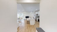 Located at 802 37th Ave NW in Rochester, Minnesota, this well-appointed 2-bedroom, 3-bathroom single-floor residence offers a thoughtfully designed open-concept layout with a clean, modern aesthetic throughout. The living room is a standout feature, boasting vaulted ceilings, light hardwood flooring, a sleek linear fireplace, and multiple windows that fill the space with natural light and views of the surrounding greenery. The kitchen is bright and highly functional, showcasing white shaker cabinetry, a large quartz-topped center island with bar seating, stainless steel appliances, and contemporary sculptural pendant lighting — ideal for both everyday living and entertaining. The bedrooms are carpeted and comfortably sized, with the generously proportioned primary bedroom offering a walk-in closet with built-in shelving and hanging rods. The three bathrooms are finished with light wood-look luxury vinyl flooring and clean white walls, with at least one bathroom featuring accessibility grab bars. A dedicated laundry room houses a full-size side-by-side washer and dryer. The entrance provides a welcoming transition into the home. Throughout, the unit maintains a cohesive neutral palette with dark wood baseboards, creating a warm and polished living environment.