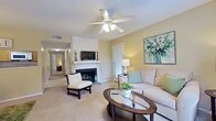 This single-floor, 2-bedroom, 2-bathroom residence at 7820 Millicent Way in Shreveport, Louisiana offers a comfortable and functional layout. The living room serves as the heart of the home, featuring a wood-paneled fireplace with a white mantle, ceiling fan with light fixture, and plush carpeting. Natural light filters in through windows dressed with teal curtains, and a glass-top coffee table anchors the seating area. An exterior door provides convenient outdoor access directly from the living space. The adjoining dining area includes a stylish chandelier and louvered bifold closet doors, adding practical storage. The kitchen is equipped with wood cabinetry, stone-look countertops, and standard appliances including a range, overhead microwave, and ample counter space. The primary bedroom offers a ceiling fan, natural light from a window with drapes, and a dedicated closet. The second bedroom is equally comfortable, also featuring a ceiling fan and window with natural light. Both bedrooms are carpeted. Two closets provide organized storage, including one spacious walk-in style with built-in shelving. The two bathrooms are functional and tidy, with one featuring wood-tone vanity cabinetry, stone-look countertops, and a shower/tub combination. A connecting hallway links the bedrooms and bathrooms seamlessly.