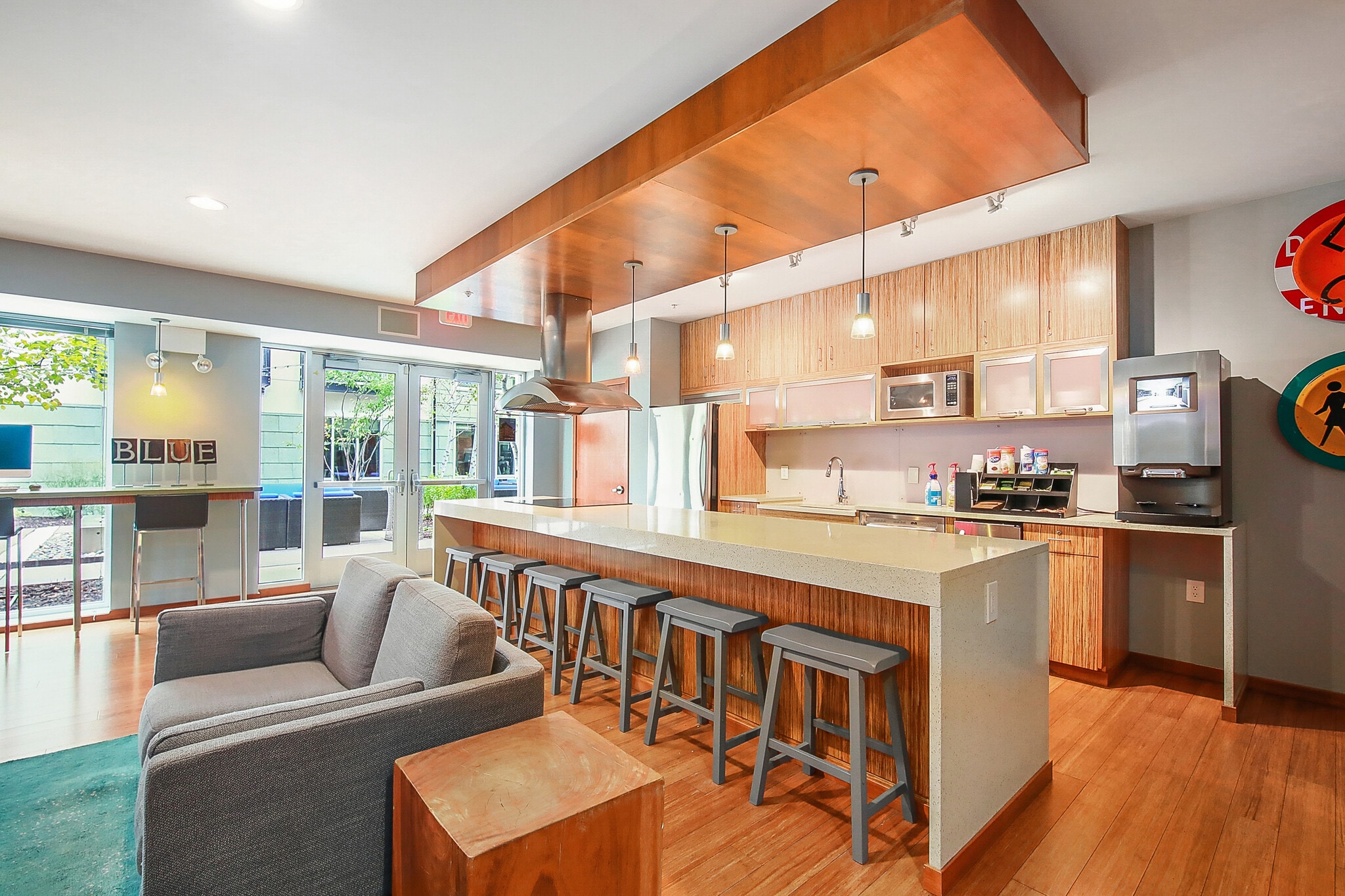 Modern communal kitchen area with a large island, bar stools, and lounge seating.