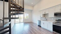 Located at 801 Pearl Street in the desirable La Jolla neighborhood of San Diego, this two-story residence offers a thoughtfully designed layout spread across two floors. The main level features an open-concept living, dining, and kitchen area bathed in natural light, with soaring ceilings that amplify the sense of space. A striking spiral staircase serves as both a functional element and a bold architectural focal point. Wide-plank wood-style flooring runs throughout, lending warmth and continuity to the interior.

The kitchen is well-appointed with crisp white shaker cabinetry accented by matte black hardware, a neutral tile backsplash, light quartz countertops, and a full suite of stainless steel appliances including a refrigerator with ice maker, range, over-the-range microwave, and dishwasher. A sliding glass door opens to a private balcony, providing outdoor access and views of the surrounding neighborhood.

The bedroom offers a generous footprint with high ceilings and direct access to a walk-in closet. The bathroom is finished in a clean, contemporary style featuring a white vanity with quartz countertop, matte black fixtures, a large mirror, and a tub-shower combination with curved glass door. An additional flexible room on the lower level provides utility as a home office or storage space.