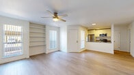 Located at 8330 N 19th Ave in Phoenix, Arizona, this single-story 2-bedroom, 2-bathroom residence offers a clean, modern design throughout. Light wood-style flooring extends across all rooms, creating a cohesive and airy atmosphere. The open living area is anchored by a ceiling fan and features built-in shelving, natural light from multiple windows with vertical blinds, and a seamless connection to the kitchen via a breakfast bar counter. The galley-style kitchen is efficiently designed with white cabinetry, granite-style countertops, and a full suite of stainless steel appliances including a refrigerator, range, and microwave. Both bedrooms are bright and well-proportioned, each equipped with ceiling fans and neutral white walls that maximize the sense of space. One bedroom benefits from built-in shelving flanked by windows, adding both functionality and character. The two bathrooms are finished with gray cabinetry, granite-style vanity countertops with undermount sinks, and full tub-shower combinations with brushed nickel fixtures. A hallway connects the living areas to the private bedrooms and bathrooms, contributing to a practical and comfortable layout throughout the home.