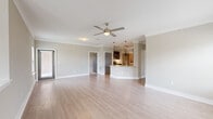 This well-appointed two-story home offers a thoughtful layout spread across two floors, with the majority of the living space located on the upper level. The heart of the home is a bright, open-concept living and kitchen area featuring light hardwood-style flooring, crown molding, and a ceiling fan. Large windows invite abundant natural light, creating an airy and welcoming atmosphere. The kitchen is outfitted with dark cabinetry, granite countertops, a tile backsplash, stainless steel appliances including a refrigerator and dishwasher, and pendant lighting over a curved breakfast bar. A dedicated laundry room is conveniently located nearby, complete with a full-size washer and dryer and overhead shelving. The two bedrooms are carpeted for comfort, each featuring ceiling fans and windows with outdoor views. The primary bedroom is generously sized and served by a full bathroom featuring a glass-enclosed shower, dual granite-topped vanity with dark cabinetry, and hardwood-style flooring. A closet provides additional storage. The ground floor houses an attached garage with an automatic opener, offering secure parking and extra storage space. Neutral tones and consistent finishes throughout lend the home a cohesive, modern aesthetic.