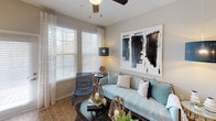 This single-floor residence offers a thoughtfully designed layout with distinct living spaces finished in a contemporary, neutral palette. The open-concept kitchen is a standout feature, outfitted with crisp white cabinetry extending to the ceiling, granite countertops, a full suite of stainless steel appliances, and a central island with bar seating illuminated by pendant lighting. Wood-look flooring flows throughout the main living areas, adding warmth and continuity.

The living room receives natural light through large windows dressed with layered blinds and sheer curtains, creating a bright and comfortable atmosphere. Multiple bedrooms are carpeted for comfort, each featuring ceiling fans, generous windows, and ample space. The primary bedroom connects to an en-suite bathroom equipped with a glass-enclosed walk-in shower, granite vanity, and wood-look flooring. A second bathroom features a soaking tub framed by large-format tile and an eye-catching geometric mosaic accent, alongside a granite-topped vanity. Throughout, the residence maintains a cohesive modern aesthetic with clean lines and quality finishes.