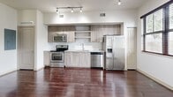 This 560-square-foot, one-bedroom, one-bathroom apartment is located at 100 NW 33rd Avenue in Pompano Beach, FL. The open-concept layout seamlessly connects the kitchen and living area, both finished with rich, dark hardwood flooring that runs throughout the unit. The kitchen is outfitted with stainless steel appliances — including a refrigerator with ice maker, range, microwave, and dishwasher — complemented by light wood cabinetry, open shelving, a white subway tile backsplash, and a granite-topped countertop. Track lighting illuminates the space, while multiple windows with dark-framed blinds invite natural light and outdoor views of the surrounding greenery. The 140-square-foot bedroom features dark hardwood floors, a ceiling fan, elevated transom-style windows, and a spacious closet with sliding panel doors. The bathroom is clean and modern, showcasing large-format tile flooring, a full tub-shower combination with floor-to-ceiling tile surround, a granite vanity with wood cabinetry, and a framed mirror. The unit's neutral color palette and contemporary finishes create a cohesive, functional living environment throughout.