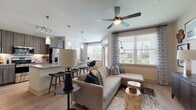 This single-story, two-bedroom, two-bathroom residence offers a thoughtfully designed open-concept layout that connects the kitchen, dining, and living areas into one cohesive, functional space. The kitchen serves as a central hub, featuring stainless steel appliances, dark wood cabinetry with a wood-grain finish, a subway tile backsplash, and a large granite-topped island with pendant lighting and bar seating. Track lighting overhead enhances visibility and adds a contemporary touch. Adjacent to the kitchen, the dining area accommodates a round table beside a window framing lush outdoor greenery, complemented by a decorative arched mirror.

The living room is bright and welcoming, with large windows dressed in patterned sheers that invite natural light and outdoor views. Wood-look flooring runs throughout the main living areas, while a ceiling fan adds comfort overhead.

Both bedrooms are carpeted and well-sized, each featuring multiple windows and ceiling fans. The primary bedroom includes an en-suite bath with a granite-topped double vanity, dark wood cabinetry, and tile flooring. The second bathroom offers a full soaking tub with white tile surround and matching tile flooring. The overall ambiance is modern, warm, and cohesive throughout.
