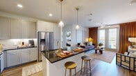 Located along E State Highway 121 N in Lewisville, TX, this thoughtfully designed 2-bedroom, 2-bathroom residence offers a comfortable and stylish single-floor layout. The open-concept living and kitchen area serves as the heart of the home, where a chef-inspired kitchen impresses with crisp grey shaker cabinetry, dark granite countertops, a stacked tile backsplash, stainless steel appliances, and a central island with bar seating illuminated by elegant brass pendant lights. Wood-look flooring flows throughout the main living areas, adding warmth and cohesion. The living room is bright and inviting, featuring a ceiling fan, large windows, and glass French doors that open to a private balcony, allowing natural light to fill the space. Each bedroom offers plush carpeting, ceiling fans, and ample natural light from generously sized windows. The spacious primary bedroom connects to a well-appointed en-suite bathroom featuring a glass-enclosed walk-in shower with marble-style tile surround, a granite-topped dual vanity with gold-accented fixtures, and wood-look flooring. Two dedicated closets provide organized storage, including a walk-in closet with built-in shelving and hanging space. The overall ambiance is modern and refined, with clean lines and upscale finishes throughout.