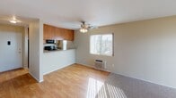 Located at 532 Broadway in El Cajon, unit #120 is a single-floor residence that combines functional design with comfortable living spaces. The layout, visible in the floor plan, reveals a well-organized arrangement of living, kitchen, and bedroom areas that flow naturally from one to the next.

The main living area features light hardwood-style flooring, a ceiling fan with integrated lighting, and a wall-unit air conditioner. Natural light enters through a window dressed with vertical blinds, creating a bright and welcoming atmosphere. A half-wall partition separates the living space from the kitchen, which is equipped with warm wood cabinetry, granite-style countertops, a black range, microwave, and a sink. Recessed lighting and a window with outdoor views complete the kitchen's functional character.

The bedrooms are carpeted and include ceiling fans, windows with vertical blinds, and generous closet space. One bedroom features a wide sliding-door closet with mirrored panels, while another includes a walk-in closet. A sliding glass door in one room opens to a private outdoor balcony area. The bathroom includes a clean, white tub-shower combination. Throughout the unit, textured accent walls add subtle architectural interest to the overall design.