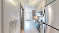This single-floor studio is designed with a clean, contemporary aesthetic that maximizes every inch of its compact footprint. Light wood-style flooring runs seamlessly throughout, complementing the crisp white walls and creating a bright, cohesive atmosphere.

The galley-style kitchen is a standout feature, outfitted with a full suite of stainless steel appliances — including a refrigerator, range, microwave, and dishwasher — paired with gray shaker-style cabinetry, granite countertops, and a tile backsplash. Track lighting illuminates the workspace, while an adjacent peninsula with additional cabinetry and counter space offers extra functionality.

The open living area benefits from a large window that invites natural light and provides views of the surrounding neighborhood. The space is versatile and well-suited for both relaxing and working from home.

The bathroom continues the modern design language, featuring gray cabinetry with granite countertops, a wall-mounted mirror, and wood-style flooring. A grab bar adds accessibility-conscious detail.

A hallway connects the rooms, lined with closet doors for built-in storage. An electrical panel is conveniently recessed into the wall. Overall, the studio presents a polished, move-in-ready living environment with quality finishes throughout.