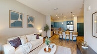 This well-appointed one-bedroom, three-bathroom residence with a den in Titusville, FL offers a smart and functional layout across a single floor. The open kitchen is a visual standout, featuring dual-tone cabinetry — light wood lower cabinets paired with bold slate-blue uppers — set against dark countertops and a striking geometric tile backsplash with stainless steel appliances. The adjoining living room is bright and welcoming, with large windows, wood-look flooring, teal accent trim, and direct access to a private balcony that overlooks a resort-style pool courtyard. The primary bedroom is generously sized, filled with natural light from a bank of oversized windows with pool views, and connects directly to a walk-in closet outfitted with wire shelving systems. The en-suite bathroom includes a glass-enclosed tile shower, granite vanity, and wood-grain cabinetry. The dedicated den/office features tall ceilings, ample natural light, and pool-facing windows, making it ideal as a workspace or flex room. Three full bathrooms provide abundant convenience for residents and guests alike. Light wood-look flooring, neutral warm-gray walls, and teal door trim create a cohesive, modern aesthetic throughout.