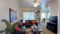 Located on East Broadway Boulevard in Tucson, Arizona, this single-story unit offers a well-organized layout that balances comfort and functionality. The living room serves as the heart of the space, featuring carpet flooring, crown molding, and a ceiling fan overhead. A sliding glass door allows natural light to filter in through sheer curtains, while a built-in shelving unit provides both display and storage space. The open sightline connects the living area to a dining space and kitchen beyond.

The galley-style kitchen is efficiently designed with light wood-tone cabinetry lining both walls, laminate countertops, and warm hardwood-style flooring. White appliances, including a range, microwave, refrigerator, and dishwasher, are neatly integrated throughout.

Two bedrooms offer carpeted floors, ceiling fans, and windows dressed with light-filtering curtains, providing a calm and restful atmosphere. Each room offers adequate space for standard bedroom furnishings.

The bathroom is a notable feature, appointed with dual sinks set into a long vanity with a stone-look countertop, a large wall mirror, wood-style flooring, and a separate tub and shower combination. A door from the bathroom provides access to additional closet space, adding to the unit's overall practicality.
