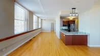 Located in the heart of downtown Saint Paul, this single-floor residence at 316 Robert St N offers a well-appointed urban living experience. Rich hardwood flooring flows throughout the open-concept living and dining areas, complemented by large windows dressed with blinds that frame views of the surrounding cityscape and fill the space with natural light. Ceiling fans are featured in the bedrooms and living areas, adding both comfort and style.

The kitchen is a standout feature, showcasing warm cherry wood cabinetry with sleek hardware, striking granite countertops with bold veining, and a full suite of stainless steel appliances including a refrigerator, microwave, and dishwasher. A kitchen island provides additional prep space and casual seating.

The bedrooms are generously proportioned, each benefiting from city-view windows and ceiling fans. The primary bedroom connects to a spacious walk-in closet outfitted with wire shelving along multiple walls for ample storage. A second walk-in closet adds further organizational capacity.

The bathroom is finished with a granite-topped vanity, rich wood cabinetry, a tiled tub-shower combination, and textured flooring. The overall aesthetic of the residence is clean and contemporary, with a warm, inviting palette throughout.