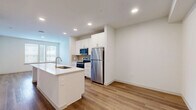 Located at 3900 PGA Pkwy in Frisco, TX, this well-designed one-bedroom, one-bathroom residence offers a thoughtful layout across a single floor. The open-concept kitchen serves as the heart of the home, showcasing white shaker cabinetry, stainless steel appliances, recessed lighting, and a large center island with a built-in sink and white quartz countertop — ideal for both meal prep and casual dining. Warm wood-look flooring flows throughout the main living and kitchen areas, creating a cohesive and inviting aesthetic. The bedroom is generously proportioned, featuring plush carpeting, a ceiling fan, and a large window that allows ample natural light and exterior views. A door from the bedroom leads directly into a spacious walk-in closet, complete with dual clothing rods and shelving for organized storage. The full bathroom is elegantly finished with wood-look flooring, a white vanity with quartz countertops, a framed mirror, a glass-enclosed shower with subway tile, and a separate soaking tub. A hallway connects the main living spaces efficiently. The overall ambiance is clean, bright, and modern, with a neutral color palette that offers a versatile backdrop throughout.