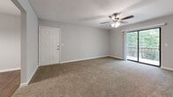 Located at 1535 Lascassas Pike in Murfreesboro, Tennessee, this single-floor 2-bedroom, 2-bathroom residence offers a practical and comfortable layout. The living room is a welcoming space featuring plush carpeting, a ceiling fan with light fixture, and a sliding glass door that opens to an outdoor balcony with lush tree views, filling the room with natural light. The kitchen is well-equipped with warm oak cabinetry, a tile backsplash, laminate countertops, and a white electric range, complemented by rich hardwood-style flooring that extends into the dining area. The spacious primary bedroom is carpeted and includes a generous walk-in closet with dual shelving on both sides, providing ample storage. The second bedroom is equally comfortable, featuring neutral carpet and clean, light gray walls. Both bathrooms are functional, with one featuring a full soaking tub and hardwood-style flooring, and the other conveniently housing a washer and dryer, adding significant utility to the home. Throughout the residence, neutral gray walls, clean white trim, and consistent flooring choices create a cohesive and move-in-ready atmosphere.