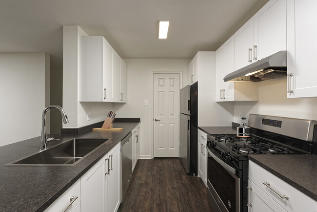 Renovated Package II kitchen with white cabinetry, dark grey laminate countertops, and stainless steel appliances, and hard surface flooring - eaves Washingtonian Center