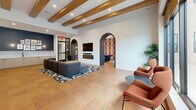 Located at 2439 Auburn Ave in Cincinnati, Ohio, this single-floor amenity space offers a thoughtfully designed communal environment spanning a generous footprint. The interior is defined by exposed wood ceiling beams, warm terracotta tile flooring, and a series of elegant arched passageways that guide movement throughout the space.

The living room serves as the central gathering area, anchored by a plush sectional sofa, a mounted flat-screen TV, and a sleek linear fireplace. Distinctive arched niches along one wall house intimate booth seating, each featuring curved upholstered banquettes, round terrazzo-topped tables, pendant lighting, and bold geometric checkered wallcoverings in earthy tones of burgundy, mauve, and tan.

Floor-to-ceiling windows along the perimeter flood the space with natural light and offer views of an outdoor terrace equipped with seating and a grill. A pair of high-back rust-orange lounge chairs positioned near the windows creates an inviting reading nook.

The dining and game area transitions seamlessly from the lounge, highlighted by a full-size billiards table beneath a circular pendant light. Surrounding this area are built-in shelving, a bar-height counter with stools, and textured tile accent walls. The hallways connect each zone fluidly, reinforcing the space's cohesive, modern aesthetic throughout.