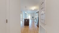Located in Mechanicsburg, Pennsylvania, this single-floor residence offers a clean, modern design with a thoughtfully laid-out open-concept floor plan. The kitchen serves as the centerpiece of the living area, showcasing rich dark-cabinetry, a subway tile backsplash, granite countertops, and a full suite of stainless steel appliances including a gas range, microwave, and refrigerator. A large kitchen island with an integrated sink and pendant lighting above provides both a functional workspace and a natural gathering point that flows seamlessly into the open living area. Light hardwood-style flooring runs throughout the main living spaces, enhancing the bright and airy atmosphere created by the white walls and generous natural light from large windows. A dedicated bedroom features plush carpeting and a sizable window with views of the surrounding greenery, offering a quiet and comfortable retreat. The bathroom is finished with dark wood cabinetry, a white countertop vanity, a large wall mirror, and hardwood-style flooring, maintaining the consistent modern aesthetic found throughout the unit. Additional utility areas, including what appears to be a laundry closet, add practical convenience to this well-appointed single-level space.