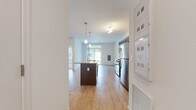 Located in Mechanicsburg, Pennsylvania, this single-floor residence offers a clean, modern design with a thoughtfully laid-out open-concept floor plan. The kitchen serves as the centerpiece of the living area, showcasing rich dark-cabinetry, a subway tile backsplash, granite countertops, and a full suite of stainless steel appliances including a gas range, microwave, and refrigerator. A large kitchen island with an integrated sink and pendant lighting above provides both a functional workspace and a natural gathering point that flows seamlessly into the open living area. Light hardwood-style flooring runs throughout the main living spaces, enhancing the bright and airy atmosphere created by the white walls and generous natural light from large windows. A dedicated bedroom features plush carpeting and a sizable window with views of the surrounding greenery, offering a quiet and comfortable retreat. The bathroom is finished with dark wood cabinetry, a white countertop vanity, a large wall mirror, and hardwood-style flooring, maintaining the consistent modern aesthetic found throughout the unit. Additional utility areas, including what appears to be a laundry closet, add practical convenience to this well-appointed single-level space.