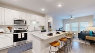 Located at 5905 Campbellton Rd SW in South Fulton, Georgia, this single-story residence delivers a thoughtfully designed open-concept floor plan with contemporary finishes throughout. The kitchen serves as a central highlight, featuring white shaker cabinetry, granite countertops, a classic subway tile backsplash, and a full suite of stainless steel appliances. A generously sized island with seating provides both additional workspace and a natural gathering point, flowing seamlessly into the living area. The living room is bright and welcoming, benefiting from natural light through large windows and a glass-panel door that opens to an outdoor area. A ceiling fan adds comfort overhead, while wood-style flooring grounds the space with warmth. The bedrooms are carpeted for comfort and include ample closet space, with the primary bedroom offering a walk-in closet and an en-suite bathroom finished with granite counters and white cabinetry. Additional bathrooms mirror the same refined aesthetic. A dedicated laundry area houses a full-size washer and dryer. Throughout the residence, neutral tones, recessed lighting, and consistent quality finishes create a cohesive, modern ambiance.