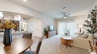 This single-story, one-bedroom, one-bathroom unit offers a thoughtfully designed open-concept layout that efficiently connects the living, dining, and kitchen areas. Light-colored walls and neutral carpet throughout create a bright, cohesive ambiance, while a ceiling fan with integrated lighting anchors the living room. Floor-to-ceiling sliding glass doors lead to a private balcony, allowing natural light to pour into the space.

The kitchen is outfitted with dark, rich cabinetry, granite countertops, a white subway tile backsplash, and a full suite of stainless steel appliances, including a refrigerator, range, microwave, and dishwasher. Light wood-style flooring and pendant lighting complete this functional space. An adjacent dining area provides comfortable space for a table and chairs.

The bedroom is a calm retreat featuring carpeted flooring, a natural light-filled window, and direct access to a dedicated walk-in closet with wire shelving. The bathroom includes a granite-topped vanity with dark cabinetry, a large mirror, and a tub-shower combination, all complemented by light wood-style flooring.