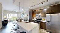 Located at 100 Colonial Homes Dr NW in Atlanta's desirable 30309 corridor, this well-appointed one-bedroom, one-bathroom residence offers a thoughtfully designed open-concept layout across a single floor. The combined kitchen and living area forms the heart of the home, anchored by a sleek quartz waterfall island with pendant lighting overhead. The kitchen is outfitted with rich dark-wood cabinetry extending to the ceiling, a full suite of stainless steel appliances including a gas range, microwave, and French door refrigerator, and a classic tile backsplash. Wood-look flooring flows throughout the main living area, which is bathed in natural light from large sliding glass doors opening to an outdoor balcony with tree-lined views of the Atlanta skyline. The bedroom is a serene retreat featuring plush carpeting, oversized windows with outdoor views, and direct access to a dedicated closet. The bathroom is elegantly finished with large-format tile flooring, a soaking tub, a dark-wood vanity with white countertop, and a framed mirror. A conveniently tucked-away in-unit laundry area with side-by-side washer and dryer completes this well-rounded residence.