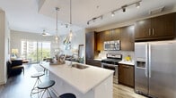 Located at 100 Colonial Homes Dr NW in Atlanta's desirable 30309 corridor, this well-appointed one-bedroom, one-bathroom residence offers a thoughtfully designed open-concept layout across a single floor. The combined kitchen and living area forms the heart of the home, anchored by a sleek quartz waterfall island with pendant lighting overhead. The kitchen is outfitted with rich dark-wood cabinetry extending to the ceiling, a full suite of stainless steel appliances including a gas range, microwave, and French door refrigerator, and a classic tile backsplash. Wood-look flooring flows throughout the main living area, which is bathed in natural light from large sliding glass doors opening to an outdoor balcony with tree-lined views of the Atlanta skyline. The bedroom is a serene retreat featuring plush carpeting, oversized windows with outdoor views, and direct access to a dedicated closet. The bathroom is elegantly finished with large-format tile flooring, a soaking tub, a dark-wood vanity with white countertop, and a framed mirror. A conveniently tucked-away in-unit laundry area with side-by-side washer and dryer completes this well-rounded residence.