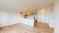 This well-appointed 2-bedroom, 2-bathroom residence offers a thoughtfully designed single-level layout with a clean, contemporary aesthetic. Light hardwood flooring runs throughout the entire unit, creating a cohesive and bright atmosphere from room to room. The open-concept kitchen and living area serves as the heart of the home, anchored by a generous peninsula with a white quartz countertop and an integrated sink. The kitchen is outfitted with stainless steel appliances — including a refrigerator, range, and microwave — alongside sleek taupe cabinetry that extends to the ceiling for ample storage. Pendant lighting above the peninsula adds a modern touch. The primary bedroom is a comfortable retreat, offering meaningful square footage, a sliding-door closet with a full-width hanging rod, and natural light from a window with outdoor views. The second bedroom also features a window with scenic views, ensuring both rooms feel bright and airy. Both bathrooms share a consistent design language, each featuring a single-sink vanity with a mirror, a tub/shower combination, and clean white finishes. A dedicated closet provides additional storage. The overall ambiance of the unit is light, neutral, and move-in ready.