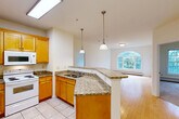 Located at 376 Quarry Hill Rd in South Burlington, Vermont, this well-appointed two-bedroom, two-bathroom residence offers a thoughtfully designed single-floor layout. The open-concept kitchen flows seamlessly into the combined dining and living area, creating an inviting, connected living space. The kitchen is outfitted with warm honey-toned wood cabinetry, granite countertops, a peninsula with pendant lighting, tile flooring, and white appliances including a refrigerator, range, and built-in microwave. A skylight overhead fills the kitchen with abundant natural light. The living area transitions to hardwood flooring and features a striking arched window that frames lush greenery outside, enhancing the sense of openness and connection to nature. A private balcony extends the living space outdoors. Both bedrooms are carpeted and offer a calm, neutral palette with large windows overlooking trees. The primary bedroom is generously sized and includes closet space, while additional closets throughout the home — four in total — provide ample storage. The two full bathrooms each feature tub-shower combinations and tile flooring with wood vanities. The overall ambiance of the home is bright, clean, and functional, making it a comfortable retreat in a verdant South Burlington setting.