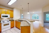 Located at 376 Quarry Hill Rd in South Burlington, Vermont, this well-appointed two-bedroom, two-bathroom residence offers a thoughtfully designed single-floor layout. The open-concept kitchen flows seamlessly into the combined dining and living area, creating an inviting, connected living space. The kitchen is outfitted with warm honey-toned wood cabinetry, granite countertops, a peninsula with pendant lighting, tile flooring, and white appliances including a refrigerator, range, and built-in microwave. A skylight overhead fills the kitchen with abundant natural light. The living area transitions to hardwood flooring and features a striking arched window that frames lush greenery outside, enhancing the sense of openness and connection to nature. A private balcony extends the living space outdoors. Both bedrooms are carpeted and offer a calm, neutral palette with large windows overlooking trees. The primary bedroom is generously sized and includes closet space, while additional closets throughout the home — four in total — provide ample storage. The two full bathrooms each feature tub-shower combinations and tile flooring with wood vanities. The overall ambiance of the home is bright, clean, and functional, making it a comfortable retreat in a verdant South Burlington setting.