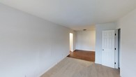 Located at Serenity, this single-floor space offers a clean and functional layout designed for comfortable everyday living. The interior is finished with neutral-toned walls throughout, creating a bright and airy atmosphere that feels open and welcoming. The main living area features wall-to-wall carpeting in a warm beige tone, providing a soft and comfortable underfoot feel, while adjacent spaces transition to rich hardwood flooring that adds warmth and visual contrast. The smooth white ceilings complement the light wall palette, contributing to a sense of openness across the floor plan. Doorways connect the spaces in a straightforward, accessible manner, with a classic paneled white door visible along one wall. The layout flows naturally from one area to the next, offering a practical and livable arrangement. The overall ambiance is clean, understated, and move-in ready, with a neutral design palette that provides a versatile canvas for a variety of interior styles and furnishing preferences.