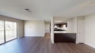 This single-floor residence offers a thoughtfully designed open-concept layout that seamlessly connects the living area and kitchen, creating a spacious and functional environment. The living area features rich, dark hardwood-style flooring and neutral-toned walls, providing a clean and versatile backdrop. A ceiling fan adds both comfort and a finishing touch to the space. Large windows allow natural light to filter in, enhancing the overall brightness of the interior.

The kitchen is a standout feature, showcasing rich dark espresso cabinetry with brushed nickel hardware, light granite-style countertops, and tile flooring. It is equipped with stainless steel appliances, including a dishwasher and range, and offers generous counter space along with a peninsula that provides additional workspace and a natural division between the kitchen and living areas.

The bathroom continues the cohesive design aesthetic, featuring the same dark cabinetry with a light granite-style vanity top, an undermount sink, and a well-lit vanity mirror. Grey tile flooring adds a polished, contemporary feel to the space.

Additional rooms, visible through connecting hallways, include carpeted bedrooms that offer a softer, more comfortable atmosphere. Throughout the residence, consistent use of neutral tones, quality finishes, and coordinated materials creates a harmonious and modern living environment.
