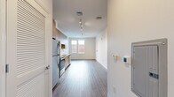 Located at 808 Chapel Street in the heart of New Haven, CT, this thoughtfully designed single-floor unit offers a clean, modern aesthetic with an efficient and functional layout. Light wood-tone luxury vinyl plank flooring runs throughout, tying together the open-plan living space and providing a warm contrast to the crisp white walls and ceilings.

The kitchen is a standout feature, outfitted with flat-front light wood cabinetry extending to the ceiling for ample storage, white quartz countertops, and a full suite of stainless steel appliances including a refrigerator, electric range, over-the-range microwave, and dishwasher. Track lighting overhead ensures the kitchen is well-lit for both cooking and entertaining.

The kitchen flows seamlessly into the open dining area, which benefits from a large window that draws in natural light and provides views of the surrounding streetscape. The open layout creates a versatile space adaptable to various furniture arrangements.

The bathroom continues the modern design language, featuring a wood-grain vanity with a white undermount sink, black matte hardware, a large mirror, wood-look tile flooring, and accessibility-friendly grab bars. The space is clean, bright, and well-appointed. Overall, the unit presents a contemporary urban living environment with quality finishes throughout.