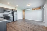 Located at 1055 Simon Crestway in Waunakee, WI, this efficiently designed one-bedroom, one-bathroom residence offers a thoughtful layout with modern finishes throughout. Light wood-tone luxury vinyl plank flooring flows through the main living areas, lending a clean and contemporary feel.

The open-concept kitchen and living room serve as the heart of the space. The kitchen is equipped with rich, dark-stained cabinetry, granite-style countertops, a stainless steel sink, and a full suite of stainless steel appliances including a range, microwave, and refrigerator. Recessed lighting illuminates the kitchen, while the adjoining living area benefits from a wall-mounted mini-split HVAC unit for year-round climate control.

The living room is bright and welcoming, featuring a sliding glass door that opens to a private balcony with a railed exterior, as well as an additional window that floods the room with natural light. The bedroom is carpeted for comfort and includes built-in wire shelving for storage, with a high horizontal window that brings in additional natural light. The full bathroom features wood-look flooring, a tub-shower combination with a curtain rod, and clean white finishes throughout.