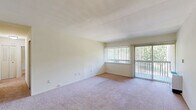 This two-bedroom, two-bathroom residence in Ypsilanti, Michigan offers a practical and well-organized single-floor layout. The combined kitchen and living room forms the heart of the home, with the living area featuring large windows and a sliding glass door that flood the space with natural light and provide views of the surrounding greenery. Soft carpeting runs throughout the living area and both bedrooms, lending a warm, comfortable feel to the interior.

The kitchen is equipped with ample upper and lower cabinetry in a classic white finish, a double-basin sink, laminate countertops, and durable tile flooring — providing a functional workspace for everyday use.

Both bedrooms are generously proportioned, with the primary bedroom offering notable space. Each room features vertical blinds over the windows, ceiling fans with light fixtures, and closet storage. The primary bedroom benefits from a dedicated walk-in closet with built-in shelving on multiple levels, maximizing storage capacity.

The two bathrooms mirror each other in design, each featuring mosaic tile flooring, a vanity with cabinetry, and a tub-shower combination with white tile surrounds, maintaining a clean and consistent aesthetic throughout. Neutral wall tones and cream-colored finishes create a cohesive, move-in-ready atmosphere throughout the entire residence.