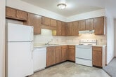 Located at 510 E 21st St in Marshfield, Wisconsin, this single-story home offers a practical and functional layout across four bedrooms, one bathroom, a kitchen, and a utility room. The kitchen is well-equipped with abundant warm-toned oak cabinetry providing ample storage, light countertops, and white appliances including a range, dishwasher, and refrigerator. Tile-style flooring runs through the kitchen area, transitioning to carpet in the living and bedroom spaces. The open living area adjoins the kitchen and features a window that allows natural light to flow through the space. Each of the four bedrooms is carpeted and includes a closet with a hanging rod for storage; several rooms feature sliding or hinged wood-panel closet doors consistent with the home's warm, neutral aesthetic. The bathroom includes a vanity with an integrated sink, wood-framed medicine cabinet with mirror, and overhead lighting. A dedicated utility room adds functional convenience. Throughout the home, wood trim accents doorways and baseboards, contributing to a cohesive and understated interior. Baseboard heating is present in the bedrooms and living areas, suited to Wisconsin's climate.