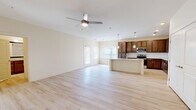 This thoughtfully designed single-floor residence offers a seamless blend of comfort and functionality across a generous floor plan. The heart of the home is an open-concept living, dining, and kitchen area bathed in natural light from multiple windows with blinds. Light-toned hardwood-style flooring runs throughout, complementing the neutral, warm wall tones that create a bright and airy atmosphere.

The kitchen is a standout feature, showcasing rich dark wood cabinetry extending to the ceiling for ample storage, a light granite-topped center island with a built-in sink, a classic subway tile backsplash, stainless steel appliances including a refrigerator, range, and microwave, and elegant pendant lighting overhead. Recessed lighting adds additional illumination throughout the space.

The spacious living area is equipped with a ceiling fan and opens comfortably for a variety of furniture arrangements. The generously sized primary bedroom features its own ceiling fan, large windows, and easy access to the full bathroom. The bathroom is well-appointed with a granite-topped vanity, a tiled soaking tub, and a walk-in closet. Additional conveniences include a dedicated laundry area, a utility room, and a private balcony.